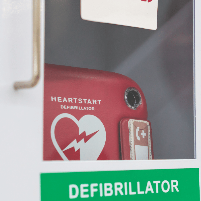 A workplace defibrillator sits in a cabinet